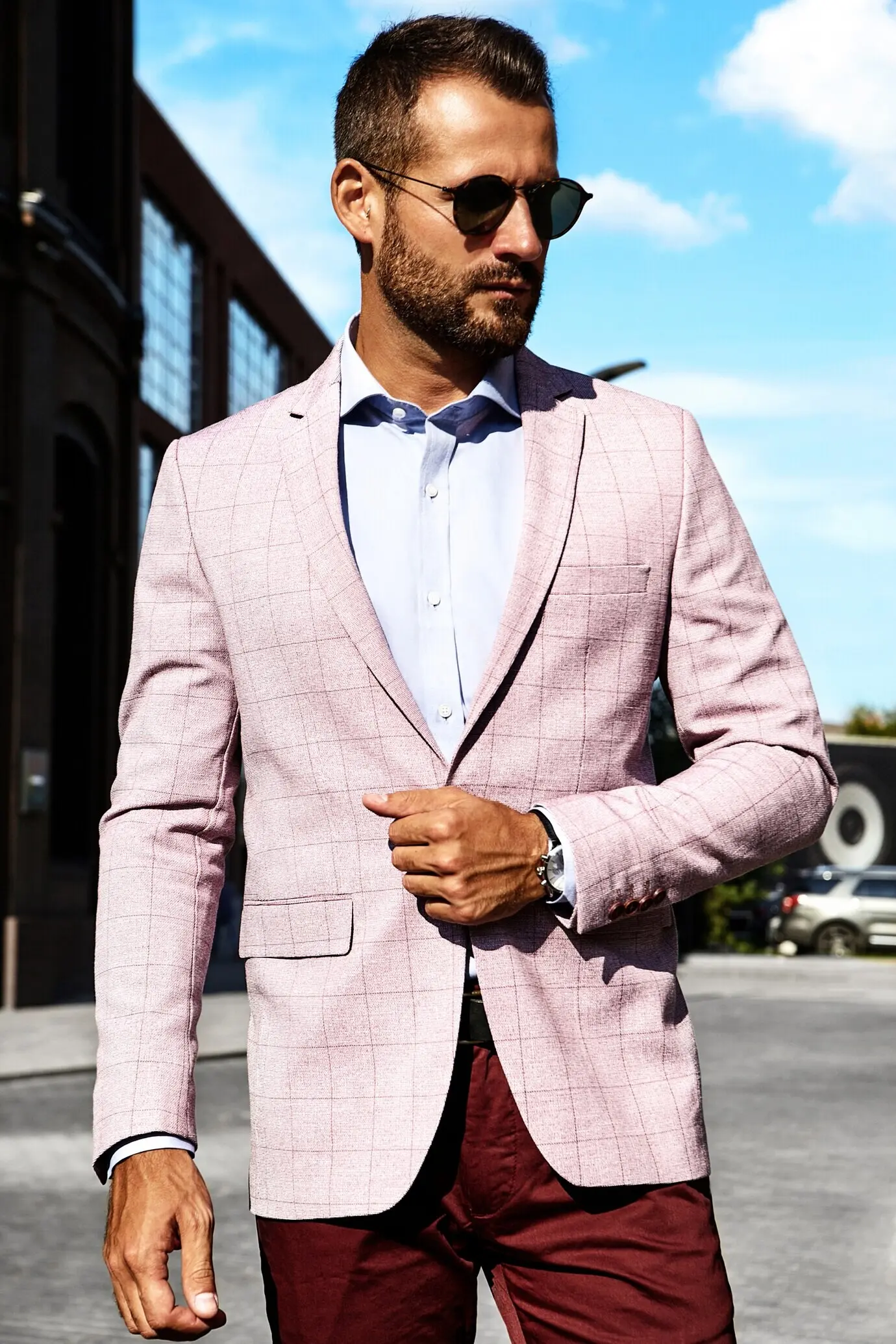 Portrait of a sexy, handsome fashion businessman model in an elegant suit posing against a street background. Metrosexual