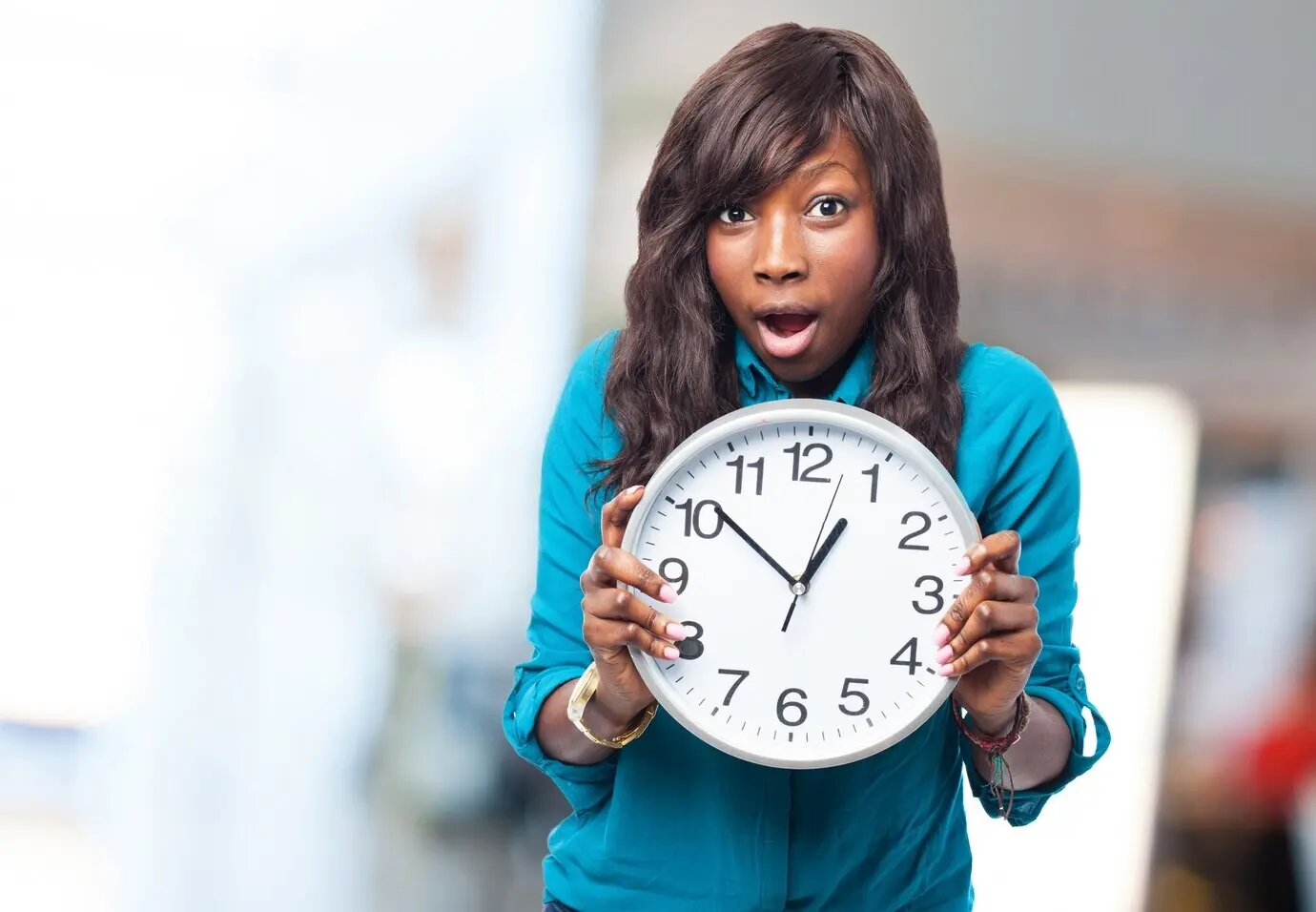 An expressive woman is holding a clock.